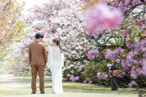 桜並木の間を新郎新婦が歩いて見つめあっている富山フォトウェディング