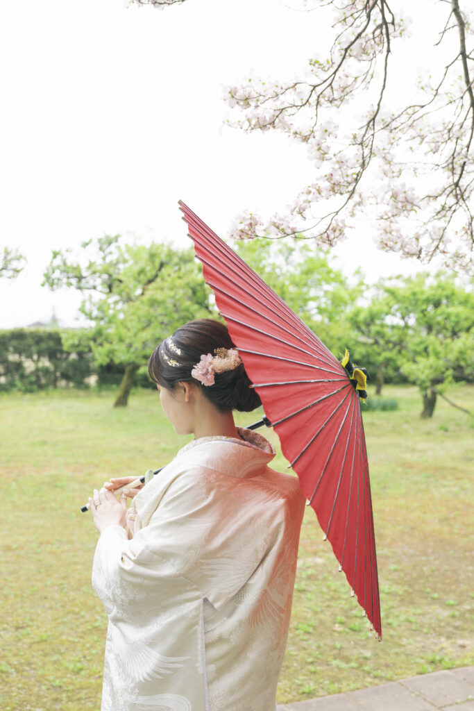 桜の下で番傘を持つ和装花嫁