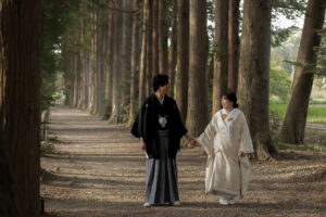 立山寺の並木道で手を繋いで歩く和装姿の新郎新婦