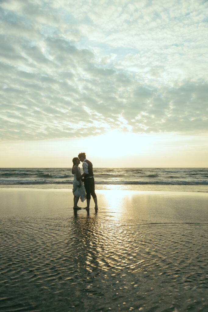 高松北部海水浴場でウユニ塩湖みたいに水面が凪になっているビーチでキスをする洋装新郎新婦のフォトウェディング