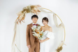 富山のフォトスタジオでドライフラワーアーチで撮影する洋装新郎新婦のフォトウェディング