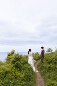 新郎新婦が海の近くの森林で空を見て立っている様子を撮影している富山ロケーションフォトウェディング