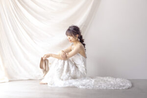 富山のコアラで洋装スタジオフォトウェディングを行った花嫁が座ってヒールを持って撮影している様子