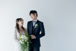 富山の洋装スタジオフォトウェディングで花嫁がブーケを持っている新郎新婦が笑い合っている前撮り写真