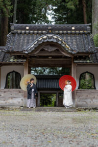 富山のコアラで和装ロケーションフォトウェディングを行なった新郎新婦が森林で赤い和傘を持ってフォトウェディング