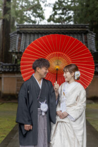 富山のコアラで和装ロケーションフォトウェディングを行なった新郎新婦が森林で赤い和傘を持ってフォトウェディング