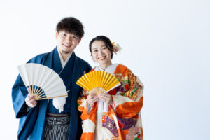 富山のコアラで和装スタジオ撮影を行なっている新郎新婦が扇子を持って微笑んでいる