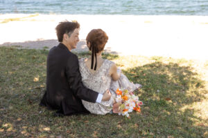 富山のコアラで洋装ロケーションフォトウェディングを行なった新郎新婦芝生に座って見つめ合っている様子