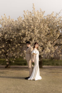 富山のコアラで春に洋装フォトウェディングを行なった新郎新婦が桜の下で撮影しているフォトウェディング