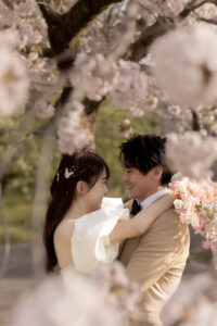 富山のコアラで洋装フォトウェディングを行なった新郎新婦が桜の下で見つめ合っているフォトウェディング