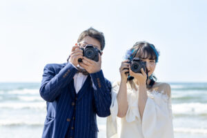富山のコアラで夏に海フォトウェディングを行なった新郎新婦がカメラを持って撮影している様子