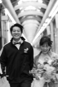 富山のコアラで街中で洋装ロケーションフォトウェディングを行なって新郎新婦が走っている様子のモノクロ写真