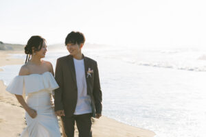 富山のコアラで海フォトウェディングを行なった新郎新婦が腕を組みながら歩いている様子